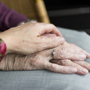 Younger female hand on top of older female hands suggesting care.