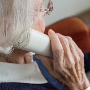 Older woman holding a phone facing away from the camera.