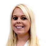 White lady with light blonde hair and dark brown eyes, wearing a white shirt and smiling.