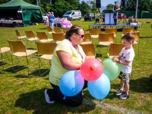 Female staff member handing out brightly coloured balloons to a young boy.