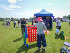 Mother and teenage daughter playing giant Connect 4 on the grass.