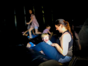 Woman and child sat inside a dark disco bouncy castle.